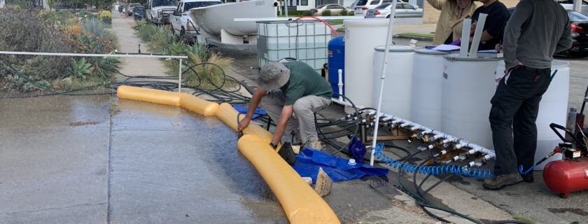 A field crew collects uses a custom-built rainfall generator to create controlled runoff conditions on a residential concrete driveway – part of a pilot study supporting an ongoing project that is measuring how much irrigation water and rainfall soaks into the ground vs. becomes runoff in residential areas. The goal is to quantify the runoff water-quality benefits of a non-structural BMP called turf replacement, which are landscaped areas where drought-tolerant plants are irrigated by drippers.