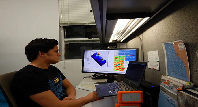 A researcher sitting at a desk examines a computer model on his screen that predicts seawater conditions along the North American West Coast.